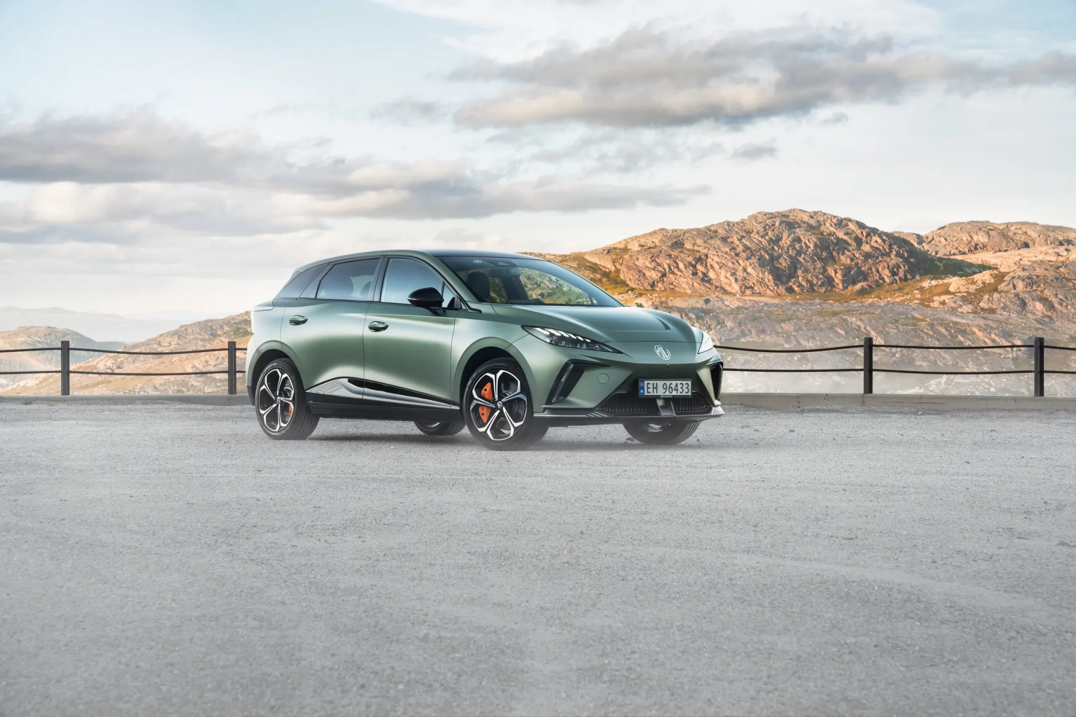 Grønn elbil-SUV fotografert ved fjellvei med utsikt over vann