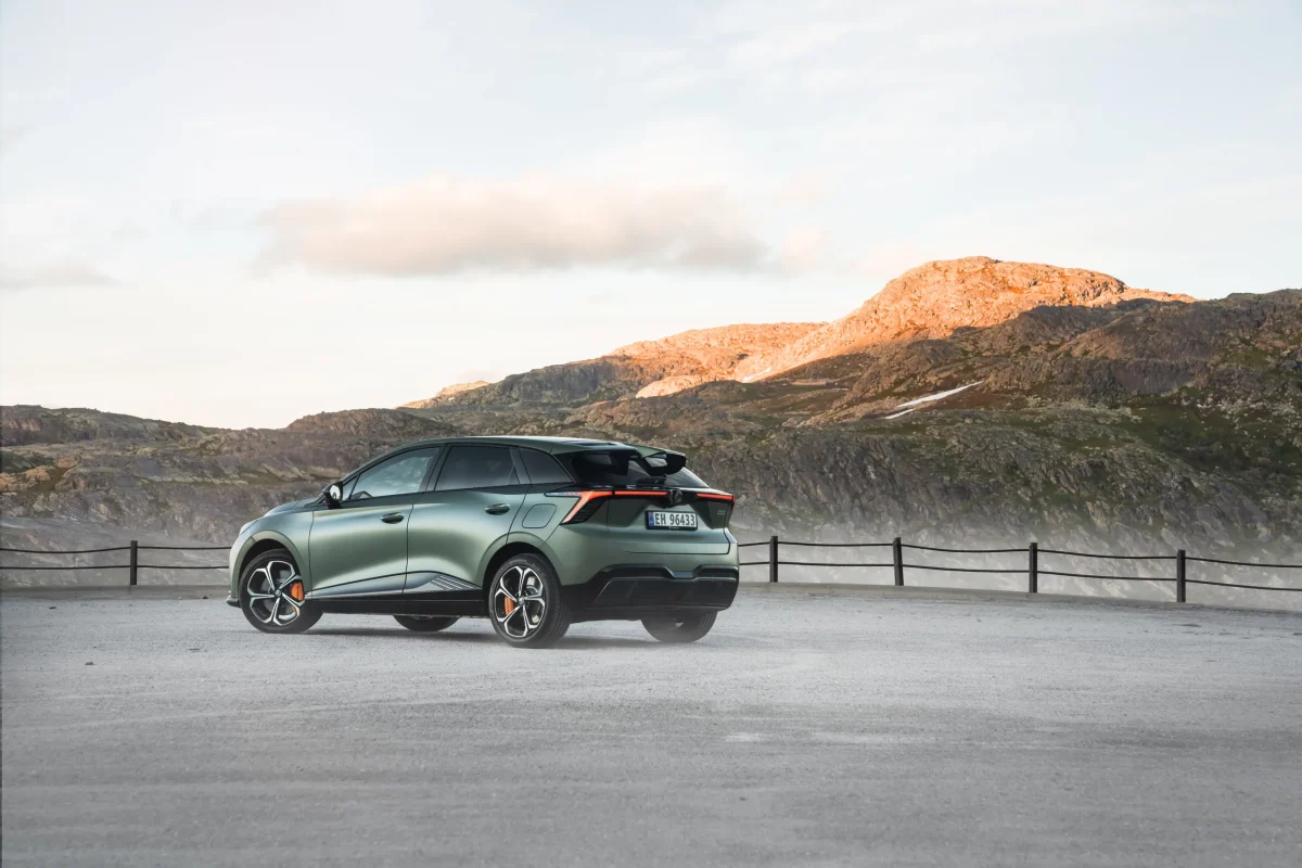 Grønn elbil-SUV på fjellvei ved solnedgang